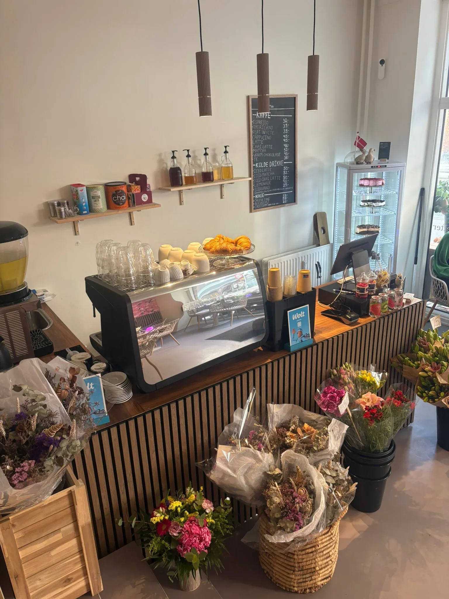 Disken med kagemontre, espressomaskine og buketter i kurve foran