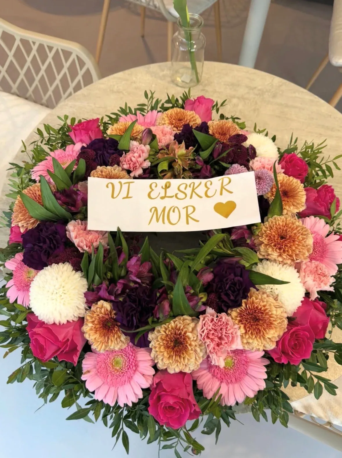 Rund buket i rosa, orange og lilla med kortet "Vi elsker mor"
